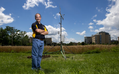 Eric Aldrich stands beside the Sanborn Field weather station on the MU campus.